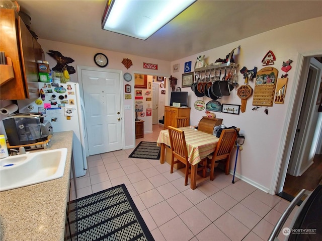 kitchen featuring sink, light tile patterned floors, and white refrigerator