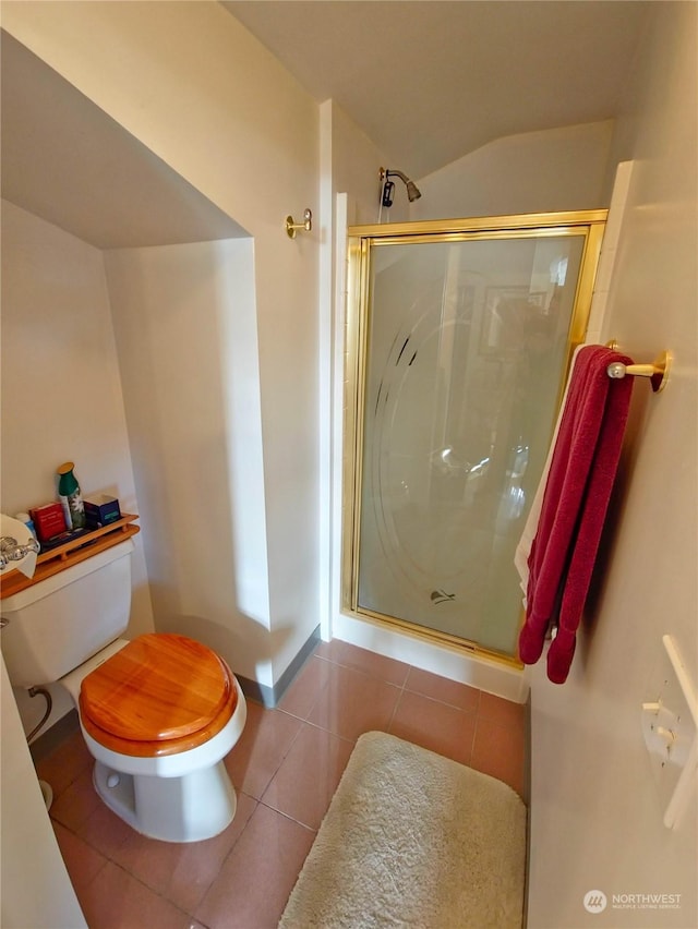 bathroom with toilet, vaulted ceiling, tile patterned floors, and a shower with shower door