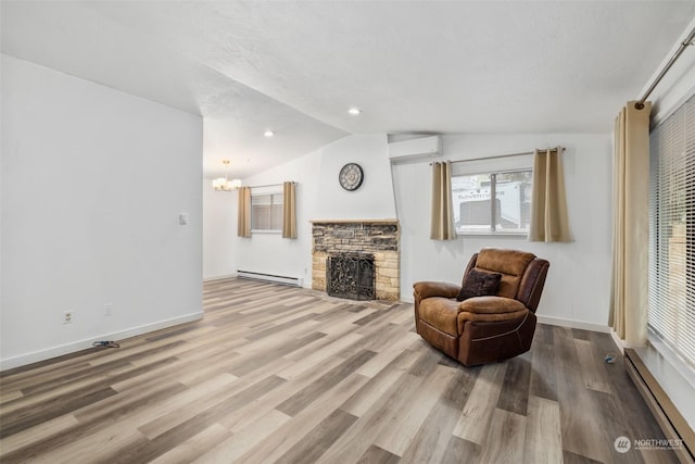 living area featuring lofted ceiling, a wall unit AC, a stone fireplace, and a baseboard radiator