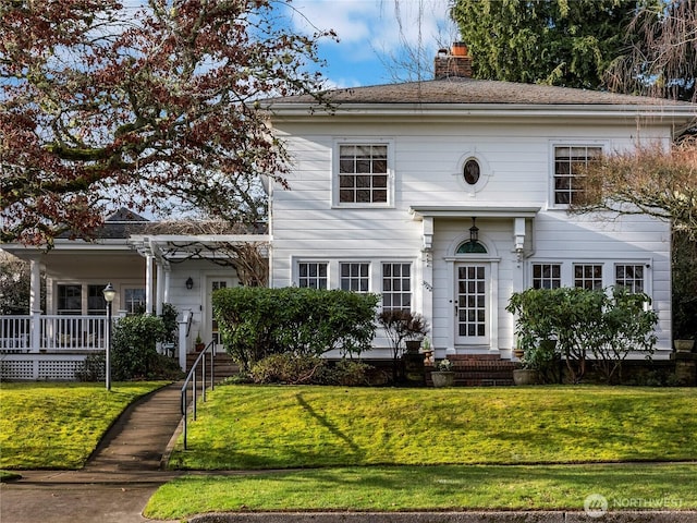 view of front of home with a chimney, a front lawn, and a pergola