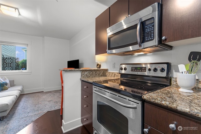 kitchen with dark brown cabinetry, dark hardwood / wood-style floors, stainless steel appliances, and stone countertops