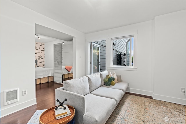 living room with heating unit and dark hardwood / wood-style flooring