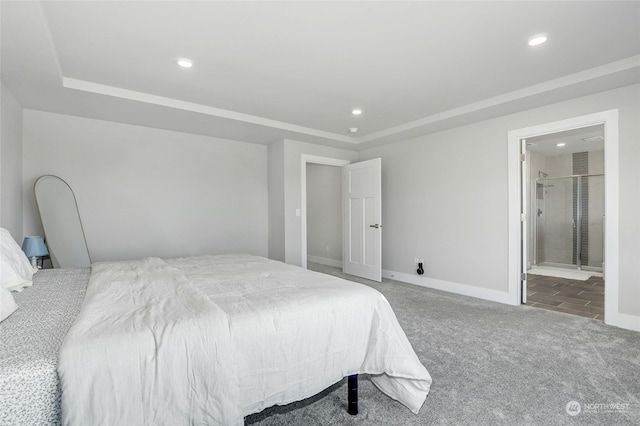 carpeted bedroom with connected bathroom and a tray ceiling