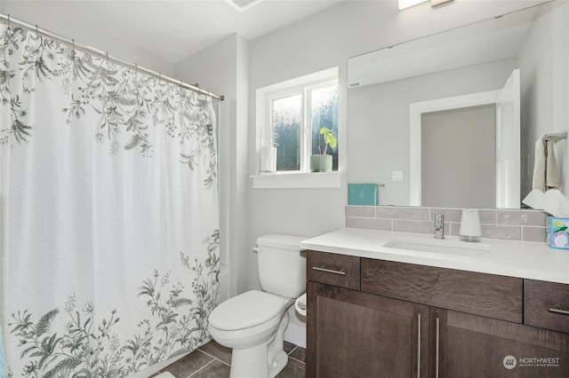 bathroom with tile patterned floors, tasteful backsplash, vanity, and toilet