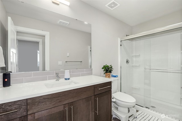 bathroom featuring vanity, toilet, and a shower with door