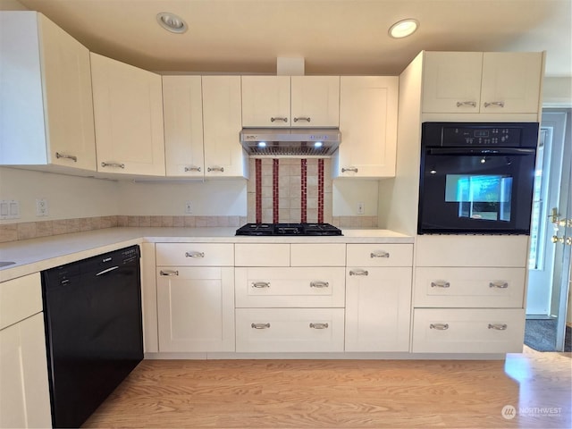 kitchen with light wood-type flooring, white cabinetry, extractor fan, and black appliances