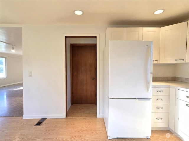kitchen featuring white cabinetry, track lighting, white fridge, and light hardwood / wood-style flooring