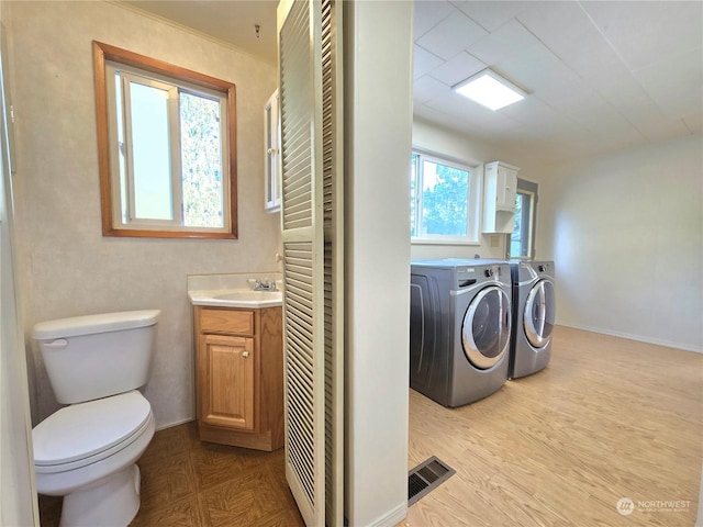 interior space featuring toilet, vanity, washing machine and clothes dryer, and wood-type flooring