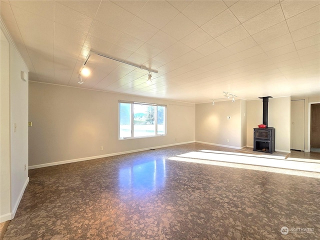 interior space featuring rail lighting, ornamental molding, and a wood stove
