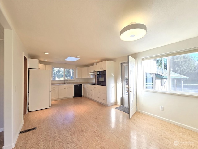 kitchen with white cabinetry, sink, black appliances, and light hardwood / wood-style floors