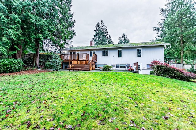 back of property with a wooden deck and a lawn