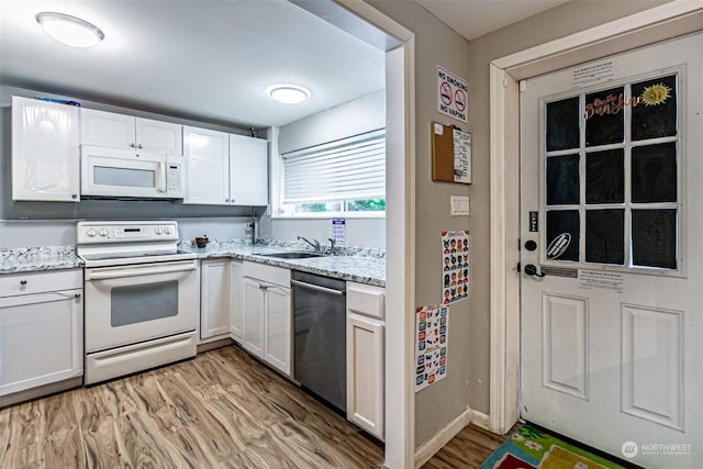 kitchen featuring light stone counters, white appliances, sink, light hardwood / wood-style floors, and white cabinetry