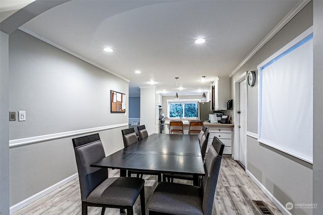 dining space featuring crown molding and light hardwood / wood-style floors