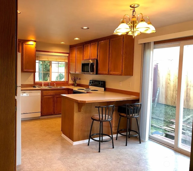 kitchen featuring kitchen peninsula, a chandelier, hanging light fixtures, electric range, and white dishwasher