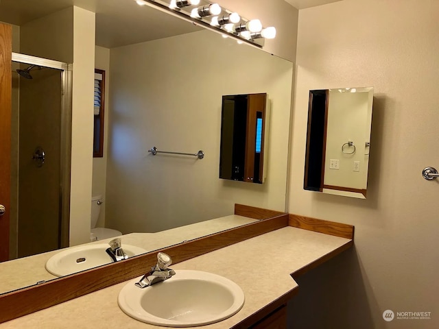 bathroom featuring toilet, a shower with shower door, and vanity