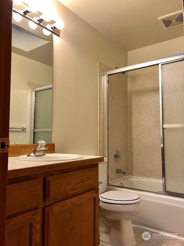 full bathroom with vanity, bath / shower combo with glass door, tile patterned floors, and toilet