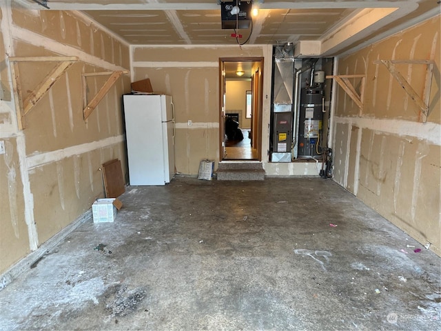 garage featuring a garage door opener, white refrigerator, and strapped water heater