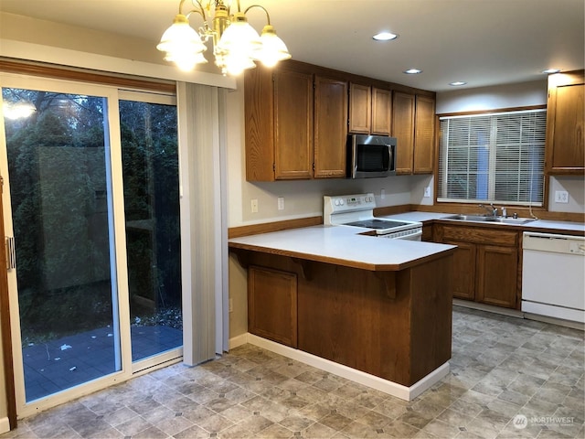 kitchen featuring sink, a kitchen breakfast bar, kitchen peninsula, pendant lighting, and white appliances