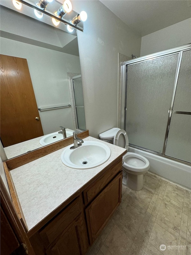 full bathroom featuring vanity, bath / shower combo with glass door, and toilet