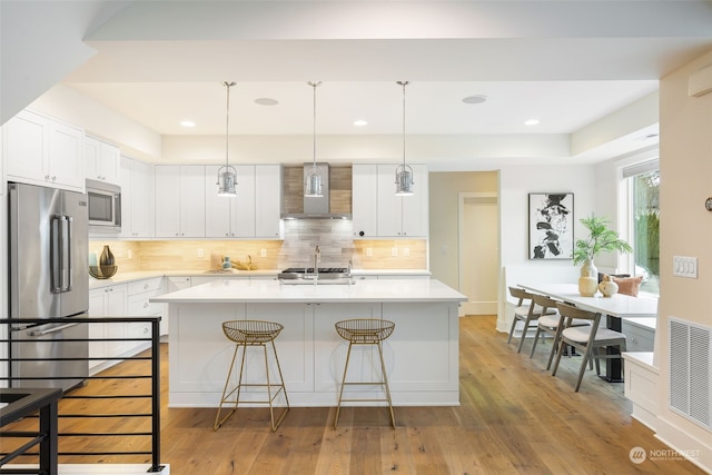 kitchen with white cabinets, stainless steel appliances, and wall chimney exhaust hood