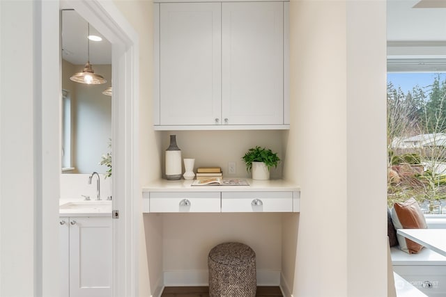 bar with white cabinetry, sink, and decorative light fixtures