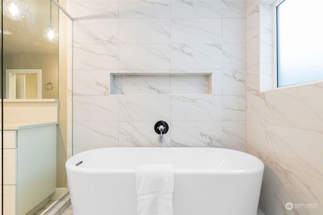 bathroom featuring a washtub, tile walls, and a healthy amount of sunlight