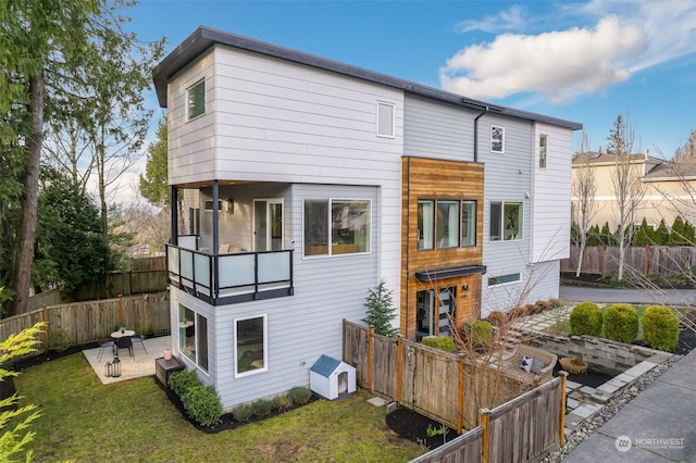 view of front of house featuring a balcony, a patio, and a front yard