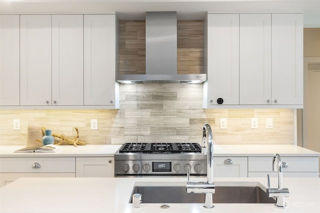 kitchen featuring decorative backsplash, sink, white cabinetry, and wall chimney range hood