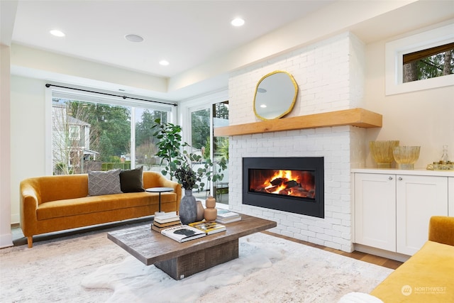 living room with light hardwood / wood-style floors and a brick fireplace