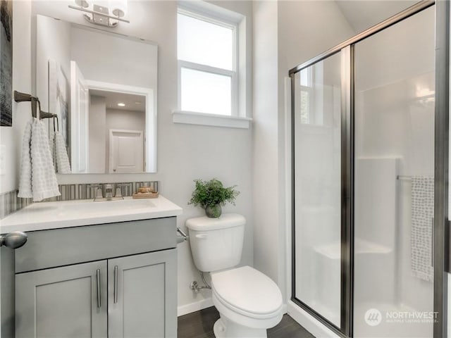 bathroom with hardwood / wood-style floors, vanity, an enclosed shower, and toilet