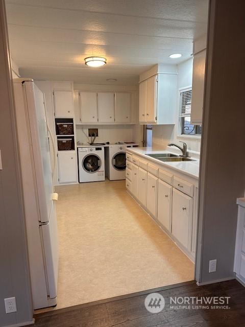 kitchen with washer and clothes dryer, white refrigerator, white cabinets, and sink