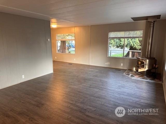 unfurnished room featuring dark hardwood / wood-style flooring and a wood stove