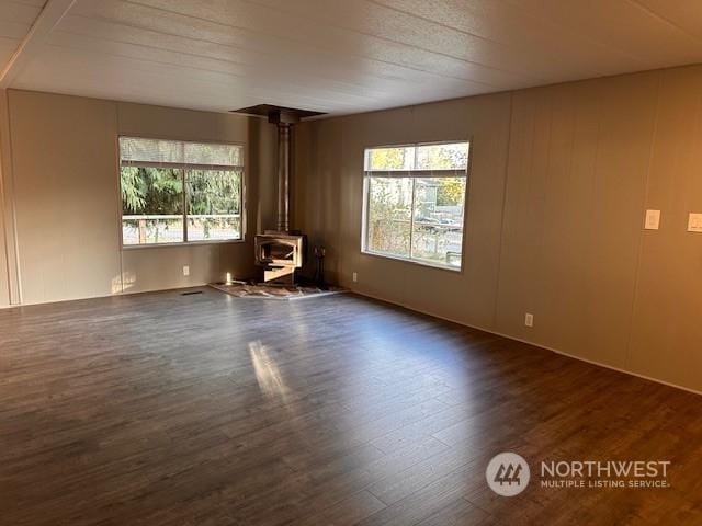 unfurnished room with a wood stove and dark hardwood / wood-style flooring