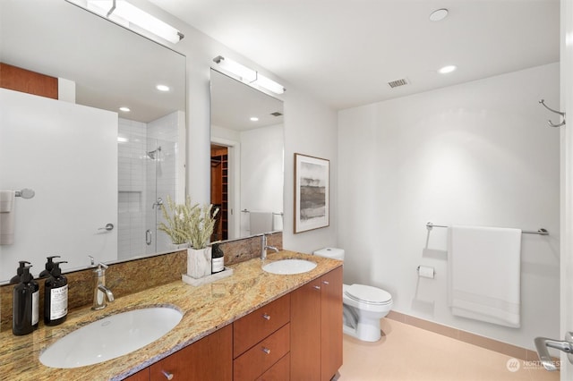 bathroom featuring tile patterned floors, vanity, toilet, and a shower with shower door