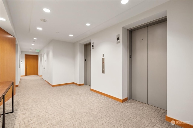 hallway featuring elevator and light carpet