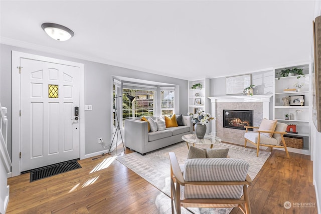 living room with crown molding, built in features, and light hardwood / wood-style flooring