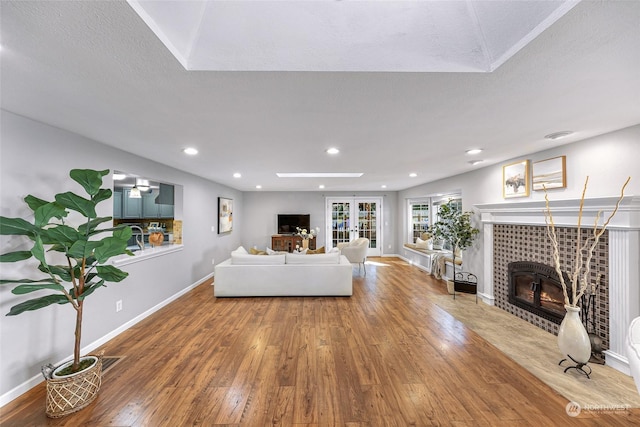 unfurnished living room featuring a textured ceiling, french doors, a fireplace, and hardwood / wood-style flooring