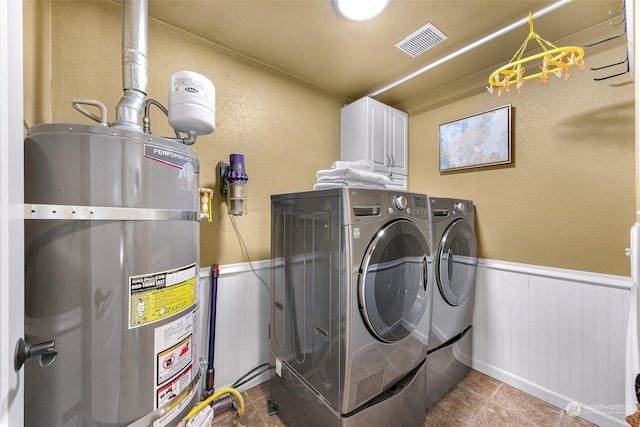 laundry area featuring tile patterned flooring, cabinets, washing machine and clothes dryer, and secured water heater