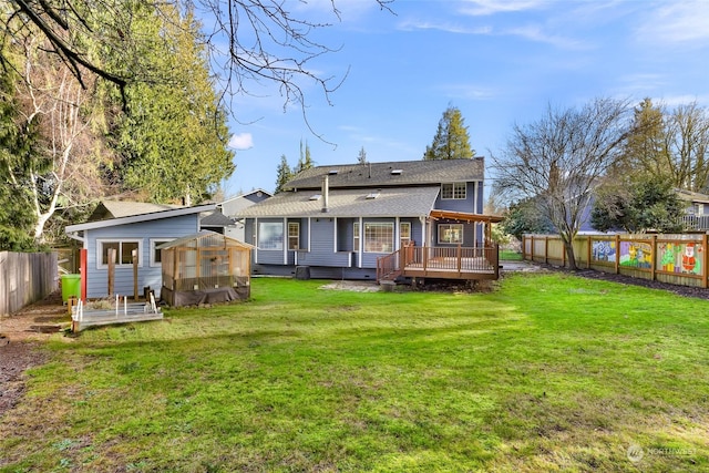 rear view of property with a deck, an outdoor structure, and a lawn