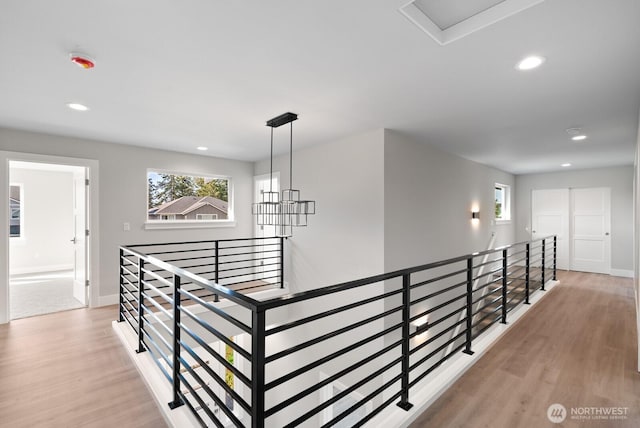 corridor with recessed lighting, an upstairs landing, light wood-style floors, and baseboards
