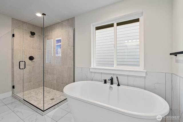 full bathroom featuring a freestanding tub, a stall shower, wainscoting, and marble finish floor