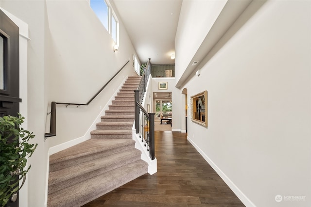 staircase featuring hardwood / wood-style floors and a towering ceiling