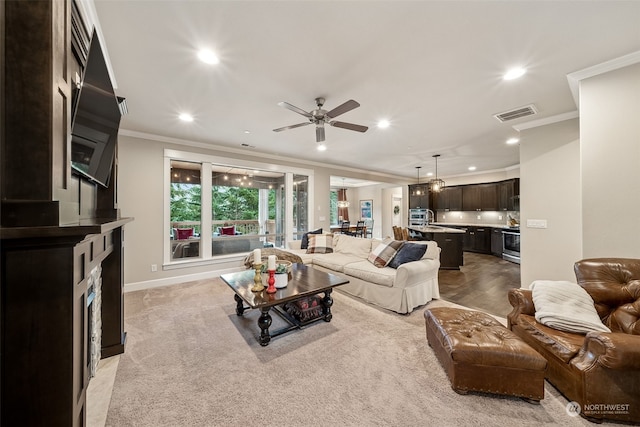 carpeted living room with ceiling fan and ornamental molding