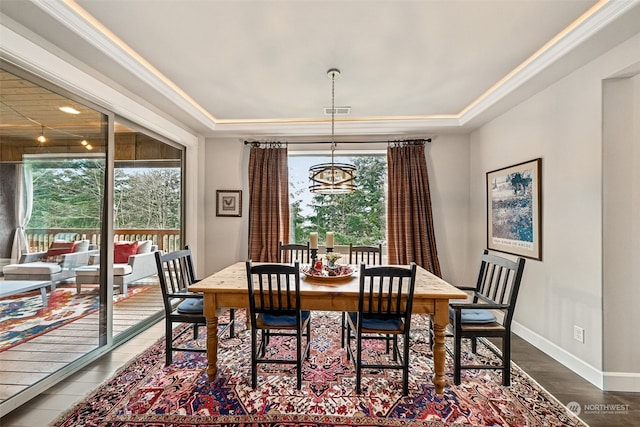 dining space with a tray ceiling, an inviting chandelier, plenty of natural light, and dark hardwood / wood-style floors