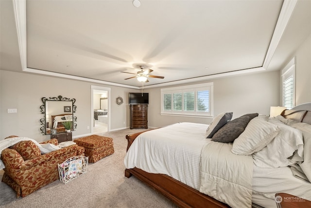 bedroom with a raised ceiling, connected bathroom, ceiling fan, and carpet flooring