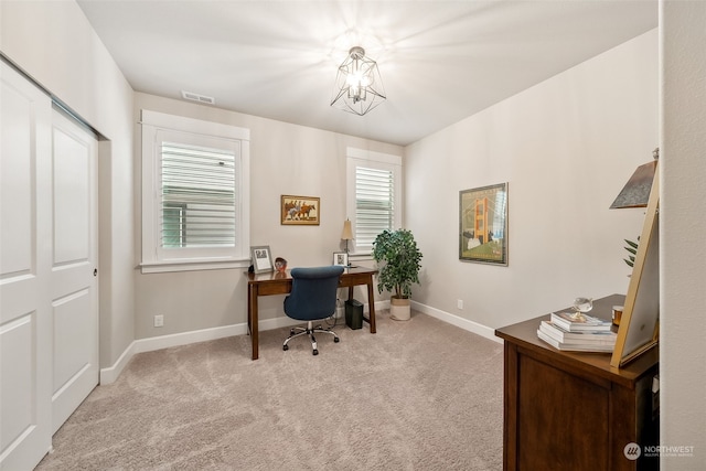 carpeted office space featuring a chandelier