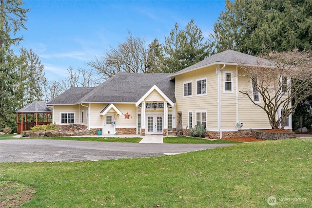 view of front facade featuring a gazebo, roof with shingles, a front lawn, and french doors