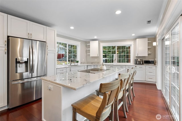 kitchen featuring a sink, a kitchen island, white cabinetry, open shelves, and stainless steel fridge