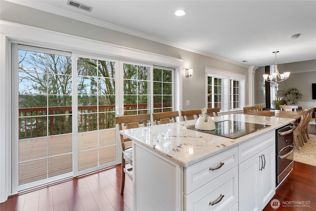 kitchen with a chandelier, black electric cooktop, dark wood-type flooring, visible vents, and ornamental molding