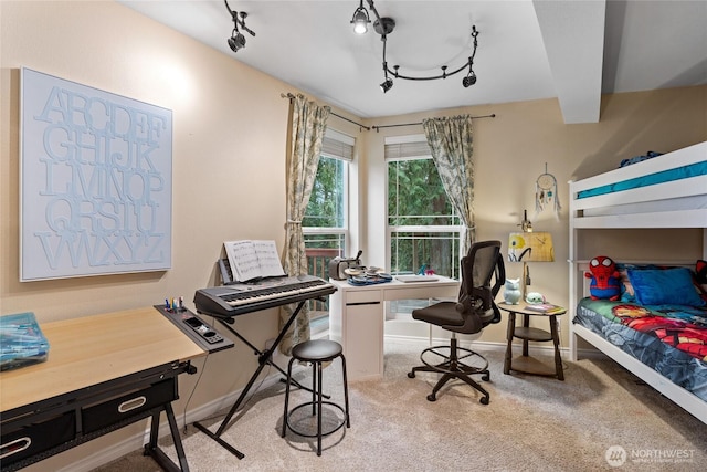 carpeted bedroom featuring track lighting, beamed ceiling, and baseboards